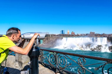 American Falls ve Bridal Veil Falls 'un güzel manzarası Niagara Şelaleleri' dir. Turist Kanada 'dan ABD' ye teleskopla bakar. Güneşli bir gün. Mavi gökyüzü.