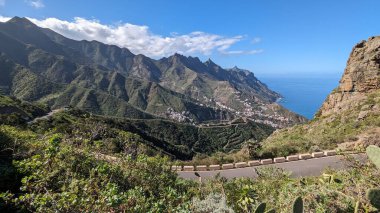 Yeşil dağlar ve uçurumlardan oluşan güzel bir manzara. Mirador Bailadero 'nun sahile ve Atlantik Okyanusu' na bakış açısı. Bulutlu mavi güneşli gökyüzü. Anaga Kırsal Parkı, Tenerife. Kanarya Adaları, İspanya.