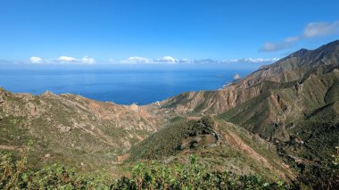 Yeşil dağlar ve uçurumlardan oluşan güzel bir manzara. Mirador Bailadero 'nun sahile ve Atlantik Okyanusu' na bakış açısı. Bulutlu mavi güneşli gökyüzü. Anaga Kırsal Parkı, Tenerife. Kanarya Adaları, İspanya.