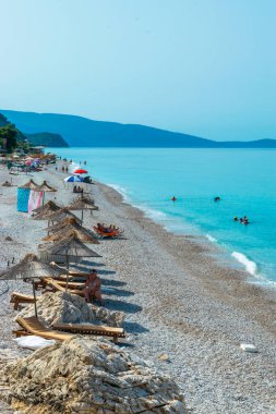 Borsh Beach, Albania - July 14, 202: Vacationers on long beach with clear blue water. Cloudless sky. Ionian Sea. Summer landscape. Concept of summer holidays and relaxation.