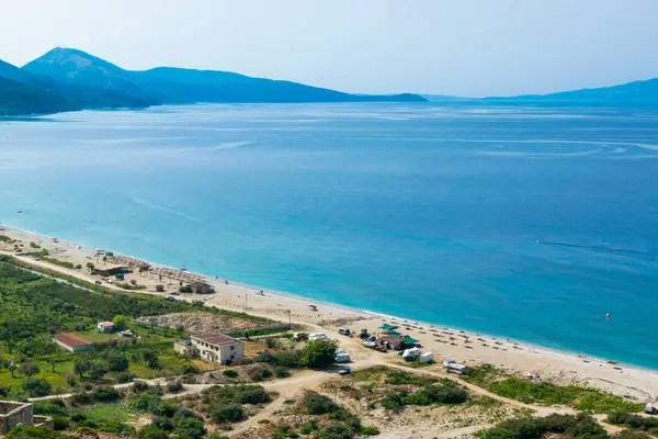 View from the top of the long sandy pebble Borsh beach. Albania. Corfu or Kerkyra island at background. Ionian Sea. Summer sunny landscape.