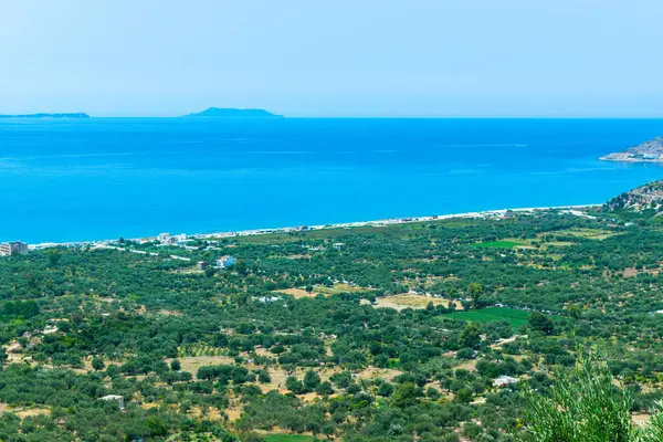 Uzun kumlu Borsh plajı ve yeşil zeytinliklerin tepesinden manzara. Arnavutluk. İyon Denizi. Yaz güneşli mavi manzara.