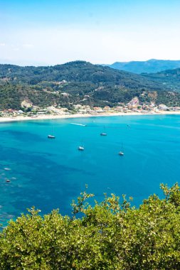 İyon Denizi 'nin gök mavisi sularından ve dağın eteğindeki Agios Georgios köyünün geniş plajlarından harika bir manzara. Plaj tatili için güzel bir yer. Korfu adası. Yunanistan.