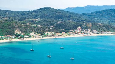 İyon Denizi 'nin gök mavisi sularından ve dağın eteğindeki Agios Georgios köyünün geniş plajlarından harika bir manzara. Plaj tatili için güzel bir yer. Korfu adası. Yunanistan.