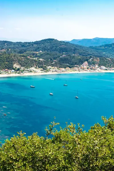 İyon Denizi 'nin gök mavisi sularından ve dağın eteğindeki Agios Georgios köyünün geniş plajlarından harika bir manzara. Plaj tatili için güzel bir yer. Korfu adası. Yunanistan.
