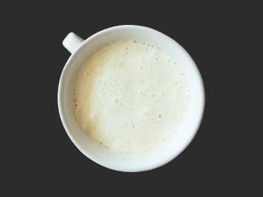 Kupadaki sütlü kahve siyah arkaplanda izole edilmiş.