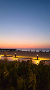 Gün batımı kumsalda oynuyor.