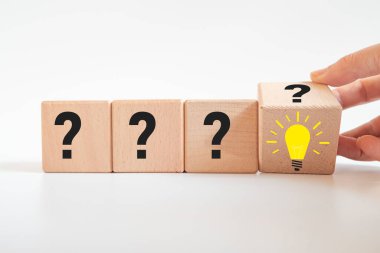 Bir soru işaretinden yanan bir ampule el yapımı ahşap küp. Yeni fikir, yeni iş hedefi, strateji, hedef planlama iş konsepti..