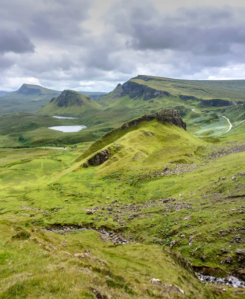 stock image Beautiful,dramatic Scottish, Skye mountain scenery,jagged peaks,winding road and sheer cliffs, along the Quiraing hills walk,green course grass covered in mid summer,in the north east.