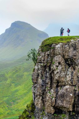 Trotternish, Skye Adası, İskoçya, İngiltere-25 Temmuz 2022: Bir yaz öğleden sonra, turistler dev, katıksız bir kaya yüzeyinin kenarında durup dramatik manzaranın fotoğraflarını çekiyorlar..