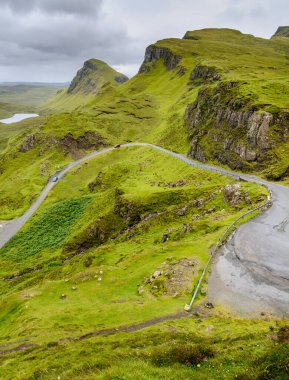Trafik için dağ yolu Quiraing yürüyüş yolunu, güzel dramatik manzaraların arasında, yağmurlu bir yaz gününde kıyıya doğru iniyor. Skye 'ın kuzey doğusunda..