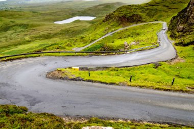Trafik için dağ yolu Quiraing yürüyüş yolunu, güzel dramatik manzaraların arasında, yağmurlu bir yaz gününde kıyıya doğru iniyor. Skye 'ın kuzey doğusunda..