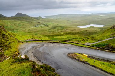 Trafik için dağ yolu Quiraing yürüyüş yolunu, güzel dramatik manzaraların arasında, yağmurlu bir yaz gününde kıyıya doğru iniyor. Skye 'ın kuzey doğusunda..
