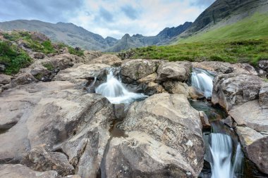 Kara Cuillin Dağları eteklerindeki uzun şelaleler ve kayalık dağ havuzları, popüler turistik yerler, muhteşem Skye manzarası, kayalarla ve yüzme alanlarıyla sarp bir yol..