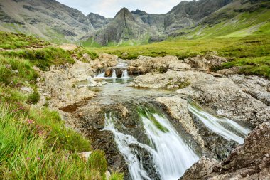 Kara Cuillin Dağları eteklerindeki uzun şelaleler ve kayalık dağ havuzları, popüler turistik yerler, muhteşem Skye manzarası, kayalarla ve yüzme alanlarıyla sarp bir yol..