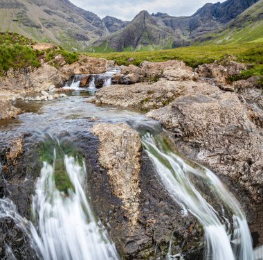 Kara Cuillin Dağları eteklerindeki uzun şelaleler ve kayalık dağ havuzları, popüler turistik yerler, muhteşem Skye manzarası, kayalarla ve yüzme alanlarıyla sarp bir yol..