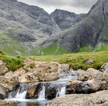 Kara Cuillin Dağları eteklerindeki uzun şelaleler ve kayalık dağ havuzları, popüler turistik yerler, muhteşem Skye manzarası, kayalarla ve yüzme alanlarıyla sarp bir yol..