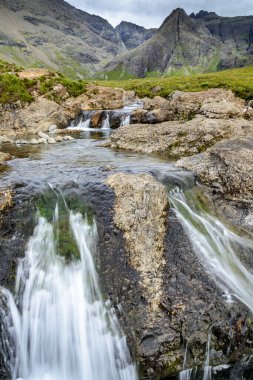 Kara Cuillin Dağları eteklerindeki uzun şelaleler ve kayalık dağ havuzları, popüler turistik yerler, muhteşem Skye manzarası, kayalarla ve yüzme alanlarıyla sarp bir yol..