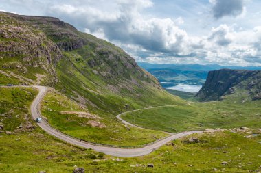 The pass of the Cattle,a winding single track road through mountains of the Applecross peninsula, in Wester Ross,Scottish Highlands.Tall cliff like mountains,rock strewn landscape,in summertime. clipart