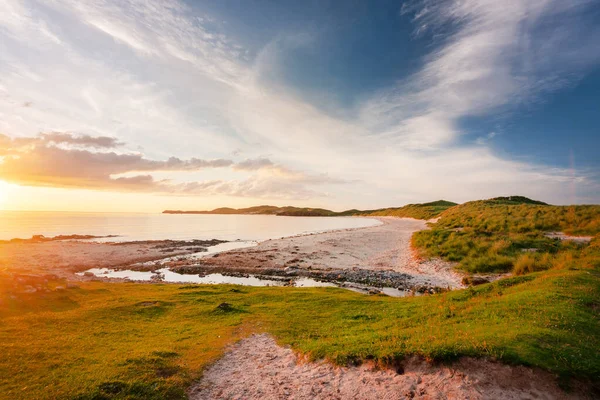 İskoçya 'nın aşırı kuzey batı ucu. Güzel kumlar ve çimenli kum tepeleri üzerinde parlayan dramatik sıcak gün batımı ışığı, ince bulutlar ve yukarıda turuncu gökyüzü, muhteşem İskoç yaz havası..