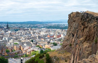 Ön plandaki Rocky uçurumları İskoçya 'nın başkentine hükmediyor. Edinburgh Kalesi Kraliyet Askeri Dövmeleri' ne, Sınır Bilim Festivali 'ne, Hub' a ve St. Mary Katedrali 'ne ev sahipliği yapıyor..