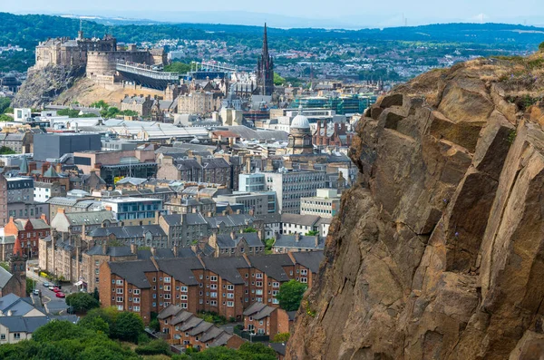 stock image Rocky cliffs in the foreground,dominate the Scotland's capital city,with famous landmarks, Edinburgh Castle set for the Royal MilitaryTattoo,during Fringe Festival,the Hub and St. Mary's Cathedral.