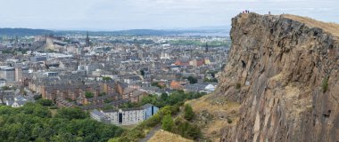 Edinburgh, İskoçya-Ağustos 01-2022: İkonik zirveye tırmanan ziyaretçiler, İskoçya 'nın başkentinde bir yaz gününde Edinburgh' un karşısındaki dev dikey bir uçurumun uçurumunda huşu içinde dururlar..