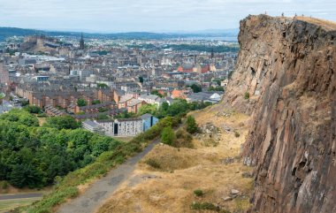 Edinburgh, İskoçya-Ağustos 01-2022: İkonik zirveye tırmanan ziyaretçiler, İskoçya 'nın başkentinde bir yaz gününde Edinburgh' un karşısındaki dev dikey bir uçurumun uçurumunda huşu içinde dururlar..