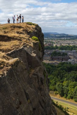 Edinburgh, İskoçya-Ağustos 01-2022: İskoçya başkentindeki güneşli bir günde, Edinburgh City 'nin etkileyici manzarasına hayran olmak için ziyaretçiler Arthur' un koltuğuna ve Crow Hill 'e tırmanıyor.