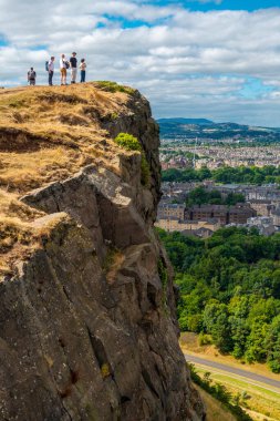 Edinburgh, İskoçya-Ağustos 01-2022: İskoçya başkentindeki güneşli bir günde, Edinburgh City 'nin etkileyici manzarasına hayran olmak için ziyaretçiler Arthur' un koltuğuna ve Crow Hill 'e tırmanıyor.