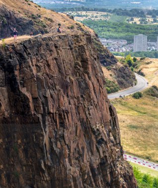 Edinburgh, İskoçya-Ağustos 01-2022: Arthur 'un koltuğuna tırmanan ziyaretçiler, İskoçya' nın başkentinde bir yaz günü, Edinburgh City 'nin karşısındaki yüksek dikey bir uçurumun uçurumunda korku içinde dikiliyorlar..