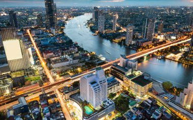 Gün batımından hemen sonra çekilen yüksek manzaralı çatı manzarası batıya bakıyor. Köprülerin ve uçurumların üzerindeki hafif tekne ve trafik yolları. Gökyüzünde parlama sonrası..