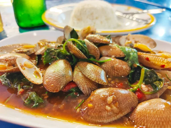 Simple delicious Thai,Bangkok street food,succulent mollusks in an oyster sauce,with garlic,chilli and green vegetables served with white rice.