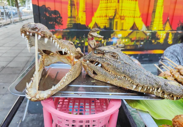 出售的鳄鱼肉 挂在竹竿上 放在银盘上晒干的头 用来为受欢迎的泰国肉做广告 在寺庙附近出售 — 图库照片