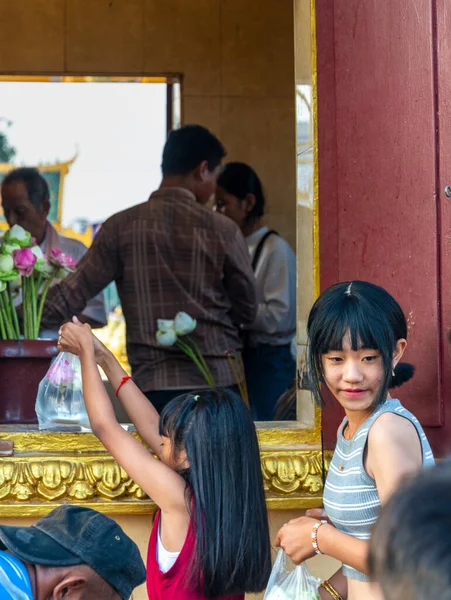 stock image Phnom Penh,Cambodia-December 23rd 2022:Giving donations of food and flowers at the holy shrine,Buddhist devotees queue up at a widow, to pass the offerings into the temple and statue of Buddha.