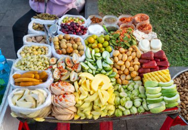 Kamboçya 'nın başkenti Phnom Penh şehrindeki Sisowath rıhtımında açık hava. Gün batımında abur cubur olarak sunulan taze, ağız sulandırıcı meyvelerin büyük çeşitliliği. Mango.