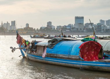 Nehrin batısından çok daha az gelişmiş çamurlu doğu kıyısında bulunan küçük tekneler, suya yansıyan güneş, küçük gemilerin ve uzak şehir binalarının siluetlerini oluşturur..