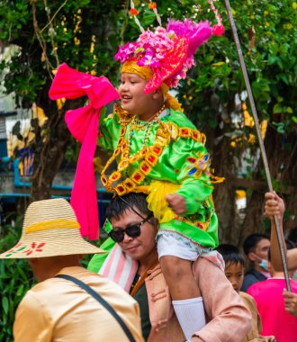 Pai, Mae Hong Son, Tayland-3 Nisan 2023: 7-14 yaşları arasında Budist rahipler olarak atanmak üzere olan çocuklar, kalabalığın kutlamalarında erkek omuzlarında sokaklarda taşınıyor..