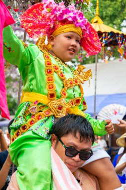 Pai, Mae Hong Son, Tayland-3 Nisan 2023: 7-14 yaşları arasında Budist rahipler olarak atanmak üzere olan çocuklar, kalabalığın kutlamalarında erkek omuzlarında sokaklarda taşınıyor..