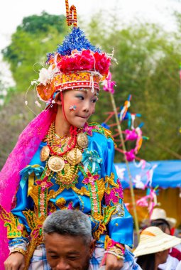 Pai, Mae Hong Son, Tayland-3 Nisan 2023: 7-14 yaşları arasında Budist rahipler olarak atanmak üzere olan çocuklar, kalabalığın kutlamalarında erkek omuzlarında sokaklarda taşınıyor..