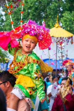 Pai, Mae Hong Son, Tayland-3 Nisan 2023: 7-14 yaşları arasında Budist rahipler olarak atanmak üzere olan çocuklar, kalabalığın kutlamalarında erkek omuzlarında sokaklarda taşınıyor..