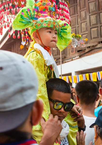 Pai, Mae Hong Son, Tayland-3 Nisan 2023: 7-14 yaşları arasında Budist rahipler olarak atanmak üzere olan çocuklar, kalabalığın kutlamalarında erkek omuzlarında sokaklarda taşınıyor..