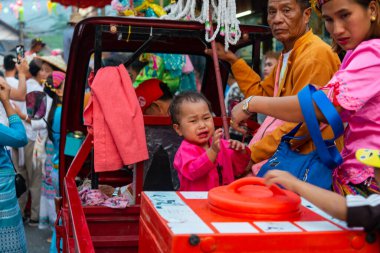 Pai, Tayland-4 Nisan 2023: Gürültülü, canlı sokak festivalinin heyecanı sırasında genç bir çocuk, Budist keşişler olarak ilan edilen erkek ve gençleri kutluyor..