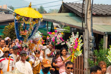 Pai, Mae Hong Son, Tayland-4 Nisan 2023: 7-14 yaşları arasında Budist rahipler olarak atanmak üzere olan çocuklar, kalabalığın kutlamaları sırasında erkeklerin omuzlarında sokaklarda taşınıyor..