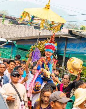 Pai, Mae Hong Son, Tayland-4 Nisan 2023: 7-14 yaşları arasında Budist rahipler olarak atanmak üzere olan çocuklar, kalabalığın kutlamaları sırasında erkeklerin omuzlarında sokaklarda taşınıyor..