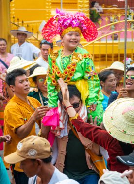Pai, Mae Hong Son, Tayland-4 Nisan 2023: 7-14 yaşları arasında Budist rahipler olarak atanmak üzere olan çocuklar, kalabalığın kutlamaları sırasında erkeklerin omuzlarında sokaklarda taşınıyor..