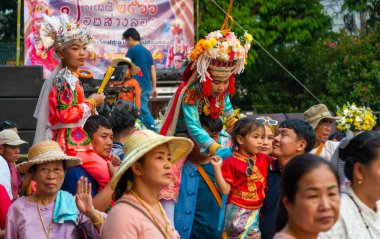 Pai, Mae Hong Son, Tayland-4 Nisan 2023: 7-14 yaşları arasında Budist rahipler olarak atanmak üzere olan çocuklar, kalabalığın kutlamaları sırasında erkeklerin omuzlarında sokaklarda taşınıyor..