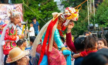 Pai, Mae Hong Son, Tayland-4 Nisan 2023: Canlı, canlı ve gürültülü kutlamaların yoğunluğundan bunalan, Budist keşiş olmak üzere olan bir çocuk, annesi tarafından pusuya düşürüldü..
