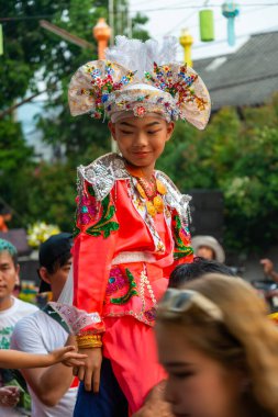 Pai, Mae Hong Son, Tayland-4 Nisan 2023: 7-14 yaşları arasında Budist rahipler olarak atanmak üzere olan çocuklar, kalabalığın kutlamaları sırasında erkeklerin omuzlarında sokaklarda taşınıyor..