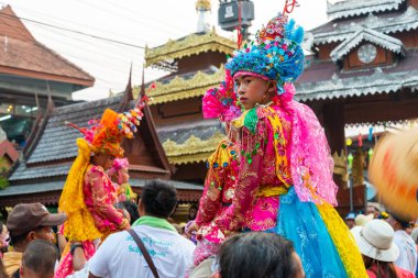 Pai, Mae Hong Son, Tayland-4 Nisan 2023: 7-14 yaşları arasında Budist rahipler olarak atanmak üzere olan çocuklar, kalabalığın kutlamaları sırasında erkeklerin omuzlarında sokaklarda taşınıyor..
